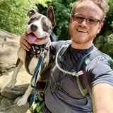 Phillip Greene on a trail with Lucky the pit bull leaning in close, both smiling